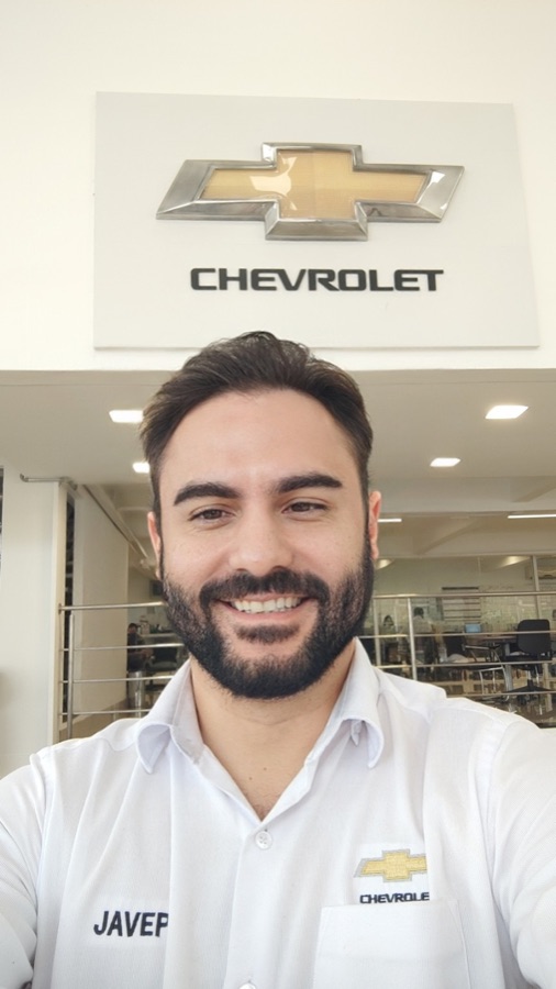 Anderson Rodrigues em frente ao logo Chevrolet na concessionária