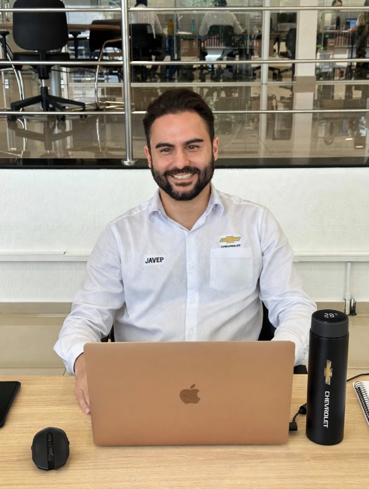 Anderson Rodrigues, especialista em consórcio, sorrindo à mesa de trabalho